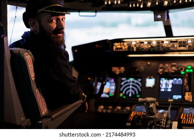 Portrait of aviator sitting in captain cabin ready to fly airplane with dashboard command buttons and power engine. Pilot flying jet for international transportation, using control panel switch.