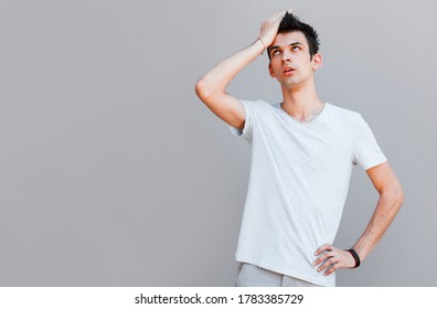 Portrait Of Awkward And Embarrassed Man Pretend He Not See His Ex, Hiding Face Behind Hand, Facepalm And Peek Through Fingers, Avoiding Eye Contact, Standing Gray Background