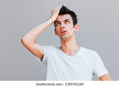 Portrait Of Awkward And Embarrassed Man Pretend He Not See His Ex, Hiding Face Behind Hand, Facepalm And Peek Through Fingers, Avoiding Eye Contact, Standing Gray Background