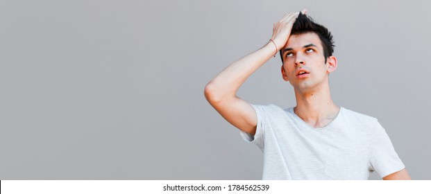 Portrait Of Awkward And Embarrassed Man Pretend He Not See His Ex, Hiding Face Behind Hand, Facepalm And Peek Through Fingers, Avoiding Eye Contact, Standing Gray Background