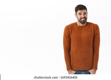 Portrait Of Awkward And Unsure Young Bearded Man Feel Discomfort, Clench Teeth And Grimacing Unwilling To Tell Truth, Standing Indecisive Trying Say Something Upsetting To Friend, White Background