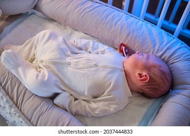 Portrait Of A Baby Boy Aged One Month Sleeping In A Crib. Caucasian Child In The Childrens Bedroom