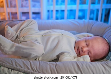 Portrait Of A Baby Boy Aged One Month Sleeping In A Crib. Caucasian Child In The Childrens Bedroom