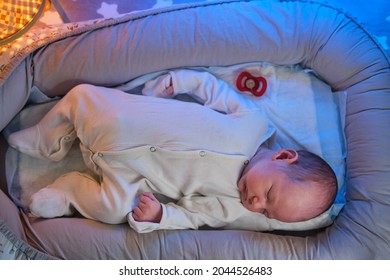 Portrait Of A Baby Boy Aged One Month Sleeping In A Crib. Caucasian Child In The Childrens Bedroom