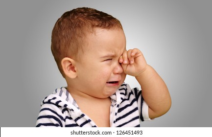 Portrait Of Baby Boy Crying against a grey background