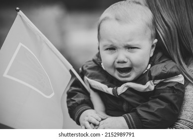 Portrait Baby Boy Crying And Call To Stop War In Ukraine Raise Flag Ukraine. No War, Stop Russian Aggression. Little Ukrainian Patriot. Sad Mother And Child Ask For Peace. Black And White Photo.