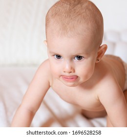 Portrait Of A Baby On A White Bed. Funny Baby Face. The Kid Stuck Out His Tongue. Educational Games With Children. Education And Care Of Newborns. The Goods For The Kids. Children's Spontaneity.