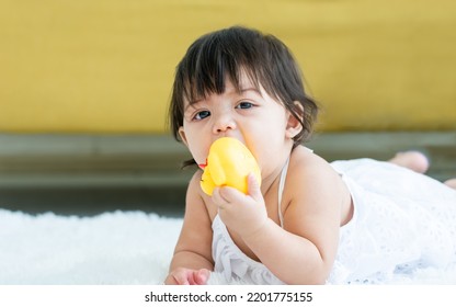 Portrait Baby Sweet Healthy Little Girl Biting Toy, Playing Alone With Happiness, Crawling On Floor In Indoor Comfortable Living Room At Home Or Apartment With Copy Space. Kid Concept