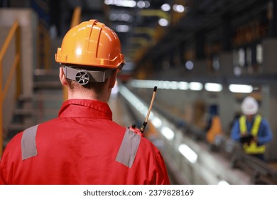 Portrait back view of technician with red safety uniform and orange hard hat Industrial and technology