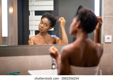 Portrait from back of young african american woman adjusting hair in mirror - Powered by Shutterstock