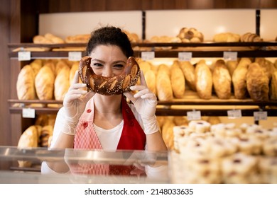 Portrait of bakery seller making funny smiling face with croissant in bakery shop.