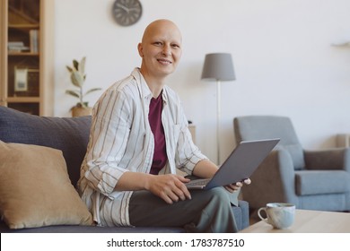 Portrait Of Bald Adult Woman Smiling At Camera While Using Laptop Sitting On Couch In Modern Home Interior, Alopecia And Cancer Awareness, Copy Space