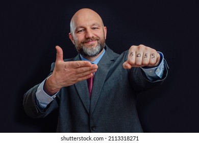 Portrait Of A Bald Business Man In Suit On Dark Background. Smile On The Face, Right Hand Points To Sign Boss On His Fist. The Model Is In His 40s, Grey And Dark Hair Beard. Good Boss Concept