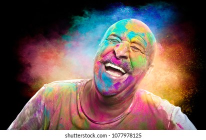 Portrait Of Bald Cheerful Man With Colored Face Celebrating Holi Color Festival. Man Having Fun With Colorful Powder. 