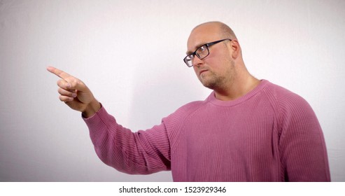 Portrait of a bald middle-aged man with glasses, he is on a white background, points his finger to the side and nods his head, then waves his finger and turns his head.