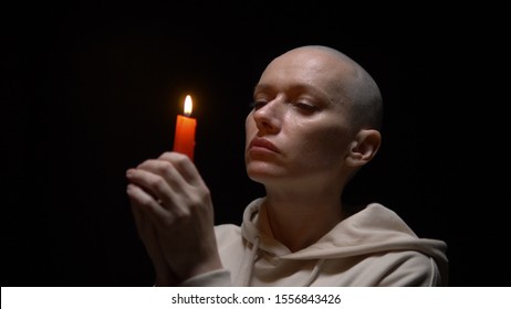 Portrait Of A Bald Woman With A Candle On A Black Background. Copy Space