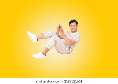 Portrait Banner Of A Young Handsome Asian Adult Man, Floating And Using Smart Phone, Isolated On Color Background. Concept Of Smart Phone Entertainment