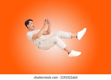 Portrait banner of a young handsome Asian adult man, floating and using smart phone, isolated on color background. concept of smart phone entertainment