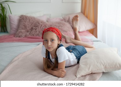 Portrait Of Barefoot Little Girl On The Bed