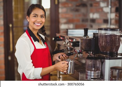 Portrait of a barista steaming milk at the coffee shop