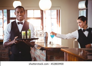 Portrait of bartender holding a serving tray with two cocktail glass - Powered by Shutterstock