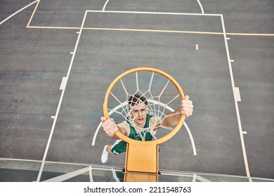 Portrait of basketball player hanging on net on a basketball court. Young man playing basketball outside doing slam dunk and jumping to score a point. Motivation to win and have fun in sports game - Powered by Shutterstock