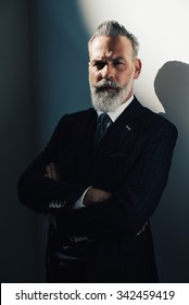 Portrait Of Bearded Gentleman Wearing Trendy Suit And Stands Against The Wall.