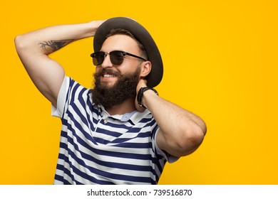 Portrait of bearded hipster man in sunglasses and hat posing on orange background.  - Shutterstock ID 739516870
