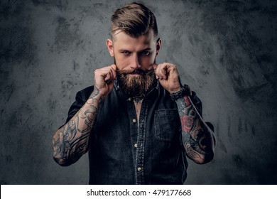 Portrait of bearded hipster with tattooe on his arms.