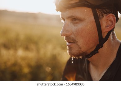 Portrait Of Bearded Man In Black Helmet Feeling Tired Because Of Riding Bike Outdoors. Strong Cyclist With Drops Of Sweat On His Face  Having Break During Training.