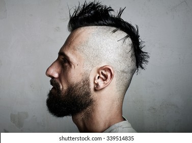 Portrait Of A Bearded Man With Mohawk. Concrete Background