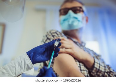 Portrait of bearded old man receiving vaccine shot in hand while wearing face protective mask during covid-19 pandemic. Medicine, vaccination and healthcare concept - Powered by Shutterstock