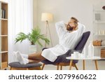 Portrait of bearded smiling man in bathrobe who is relaxing and enjoying his free time. Man putting his hands behind his head is resting in spa or at home or in hotel room. Recreation concept.