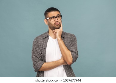 Portrait of bearded thoughtful handsome man with black glasses in casual style thinking. studio shot on blue background. - Shutterstock ID 1087677944