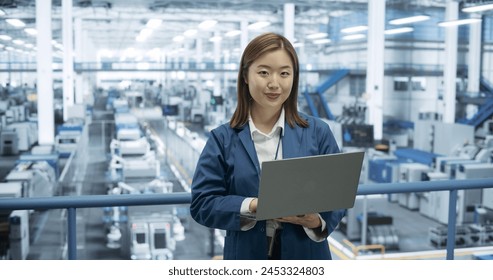 Portrait of a Beatiful Electronics Manufacture Engineer Smiling, Looking at Camera. Young Japanese Female Using Laptop Computer for Online Research, Monitoring Artificial Intelligence Systems