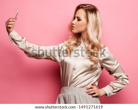Portrait of beautifu smiling blond woman in casual clothes with perfect makeup with smartphone
