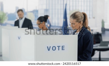 Portrait of a Beautiful Adult Woman Filling Out a Ballot in a Voting Booth on the Day of National Elections in the European Union. Diverse Men and Women Voting for Elected Officials in an EU Country