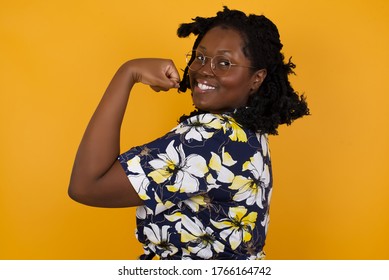 Portrait of beautiful African American woman isolated over yellow background,  showing muscles after workout. Health and strength concept. - Powered by Shutterstock