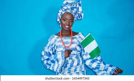 Portrait of a beautiful African woman dressed in Yoruba traditional attire and waving the Nigerian flag