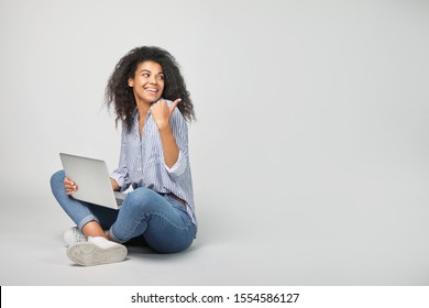 Portrait of a beautiful african woman with laptop on grey background - Shutterstock ID 1554586127