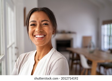 Portrait of a beautiful african woman smiling while looking at camera. Mature black woman in casual standing near window at home. Close up face of laughing cheerful lady near window with copy space. - Shutterstock ID 2012714192