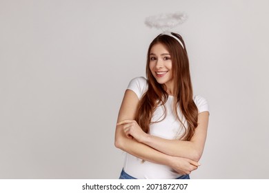 Portrait of beautiful angelic woman looking smiling at camera, expressing positive expression, self-love concept, wearing white T-shirt. Indoor studio shot isolated on gray background.