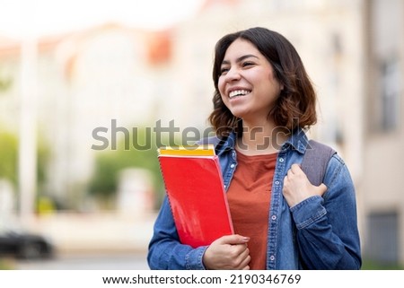 Portrait Of Beautiful Arab Female Student With Workbooks In Hand Posing Outdoors, Smiling Young Middle Eastern Woman In Casual Clothes Standing Outside At College Campus, Holding Notepads