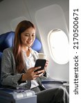 Portrait, Beautiful asian businesswoman at her seat having a hot morning coffee and using a mobile phone to check her meeting schedule during a flight to the next city.