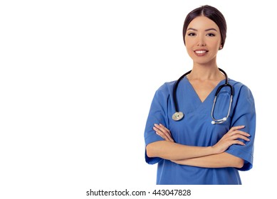 Portrait Of Beautiful Asian Female Doctor In Blue Medical Wear Looking At Camera And Smiling While Standing With Crossed Arms, Isolated On White Background