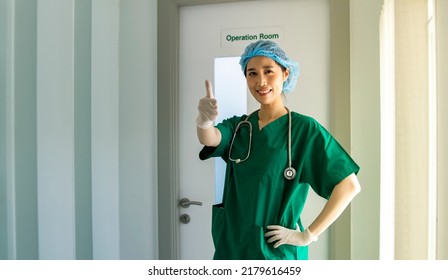 Portrait Beautiful Asian Female Surgeon Wearing Thumbs-up Mask Satisfied Saving Emergency Patients From Harm : Successful Surgery And Congratulations Happy Smile Stood In Front Of The Operating Room.