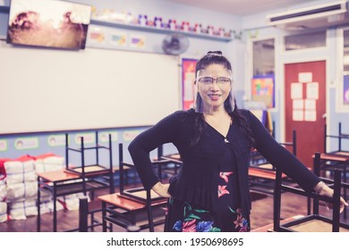 Portrait Of Beautiful Asian Female Teacher Wearing Face Shield Smiling  While Standing In The Classroom. New Normal Lifestyle During Corona Virus Or Covid-19 Crisis