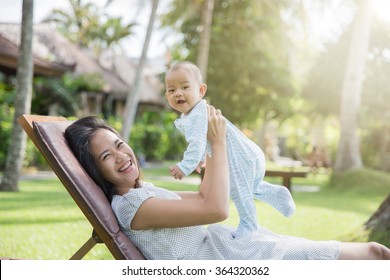 Portrait Of A Beautiful Asian Mother Having Fun With His Baby On A Sunny Day