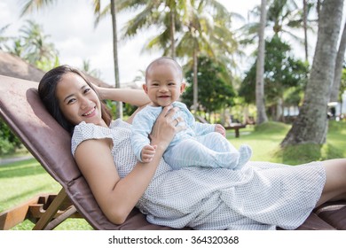 Portrait Of A Beautiful Asian Mother Having Fun With His Baby On A Sunny Day