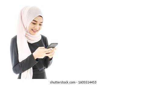 Portrait Of Beautiful Asian Muslim Woman In A Black Hijab Smiling And Using Mobile Phone Isolated Over White Background